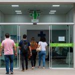 People waiting and entering a modern community health center in a Brazilian city.